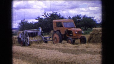1963: Tractor Pulling Combine Harvesting Hay Bales with Worker Stacking