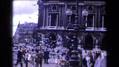 1963: people's walking around big building's and bird flying around at daytime