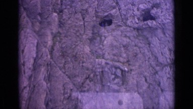 1962: people stand in mouth of caves on sheer rock face of huge mountain