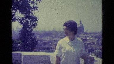 1962: woman points at church standing above city skyline on hazy day VATICAN