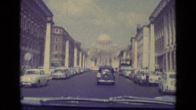 1962: cars drive down distinguished street toward ornate domed building VATICAN