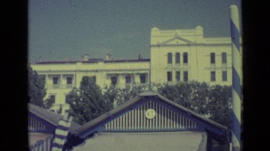 1962: Big White Building Behind Trees, Woman Instructing Near Shelter