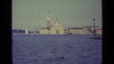 1962: Traveling Across Water Passing Boats and Buildings with White Table