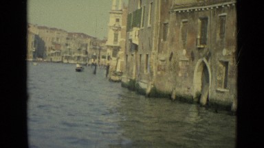 1962: traveling slowly in boat along venice canal, passing by old buildings.