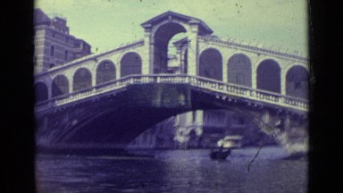 1962: boat going under bridge as man approaches paddling another boat. VENICE