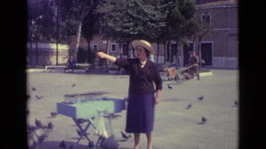 1962: man dressed in business suit and woman feed flock of pigeons
