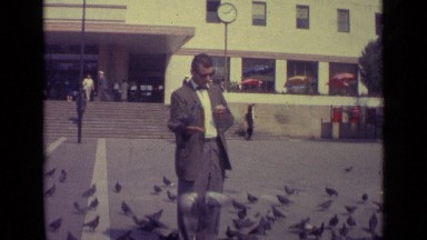 1962: feeding birds in courtyard of busy city during day as others pass by