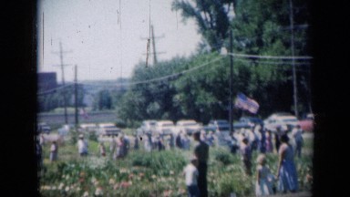 1961: gathering of many people of different ages walking through open area