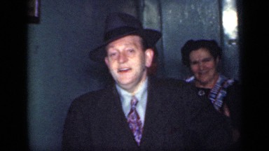 1949: old men and women coming out of building and men smiling and removing hat
