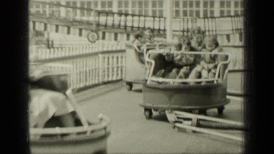 1949: Adults and Children Speeding Around on Whip Ride in Amusement Park