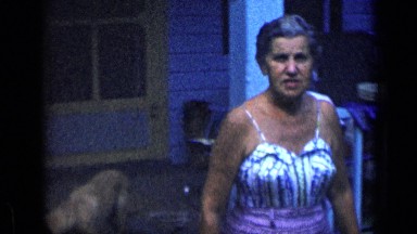 1957: middle aged lady smiling and waving at someone outside her house NEW YORK