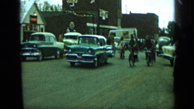 1959: man riding in horse,children cycling back to horse and peoples are going