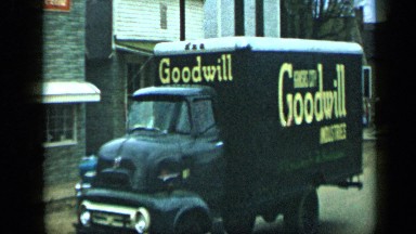 1959: truck and car is moving slowly on road and car is parked alongside road