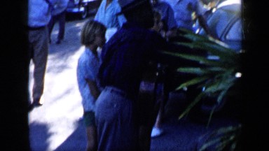 1959: Man Holding Guitar and Wearing Hat Speaks and Gestures with Tourists