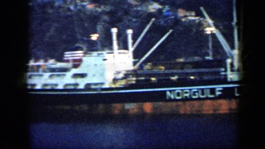 1959: lots of ships are berthed alongside jetty and in line at narrow river