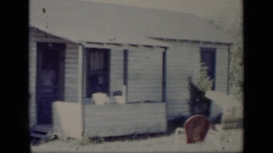 1948: man opening front screen door of old house and waving at camera NEW YORK