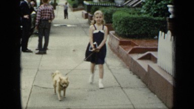 1948: Pretty Blonde Girl in Blue Sundress Walking Her Small Dog