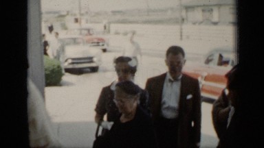 1948: old people talking together and men's wearing black suit and car parked