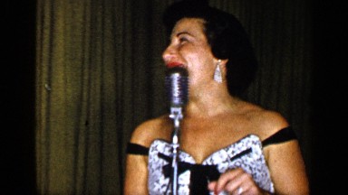 1948: woman sings on stage accompanied by saxophonist, pianist and drummer