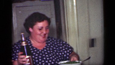 1949: robust woman bringing beverage and green vegetables to her family