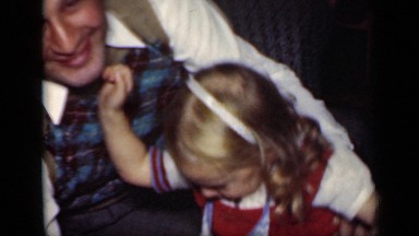 1949: white man seated on sofa gives young girl kiss NEW YORK