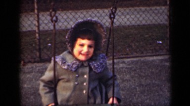 1949: little boy running behind little girl to push her on swing NEW YORK