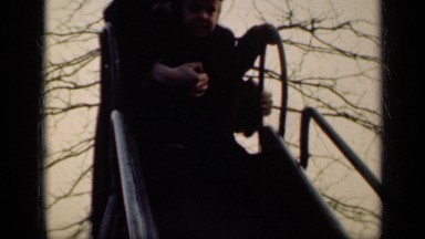 1949: father pushing his daughter down slide at park. NEW YORK
