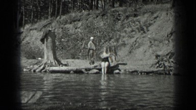 1939: a guy is swimming in the water, some people on the bank of the river