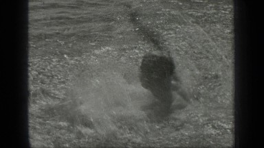 1939: a man is swimming vigorously in the water towards another man