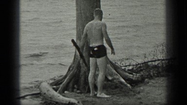 1939: man in bathers carries driftwood at a beautiful beach. LONG LAKE CANADA