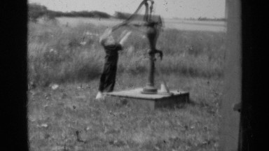 1947: vintage footage of young child hand pumping a drink of water from a well