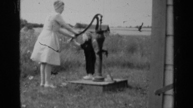 1947: a woman teaching her baby how to get water from the water mortar and kid