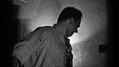 1947: scene of a man talking with someone, pacing around the room, smiling