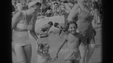 1947: mother and daughter helping baby brother walk along the coast NEW YORK