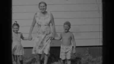 1947: mother and her two children walking in the lawn near house NEW YORK