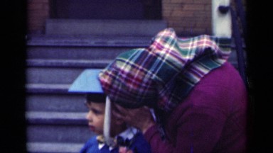 1948: a mother adjusts a graduation cap on a smiling boy at the foot