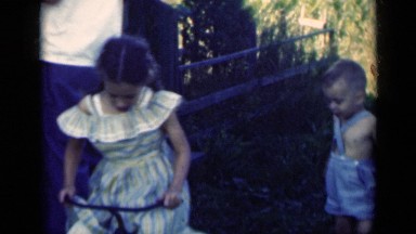 1948: two kids playing with a small bicycle on the grassy ground INDIANA