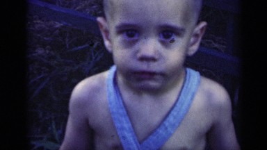 1948: young boy with large and dark eyes stares, looks, reaches and smiles