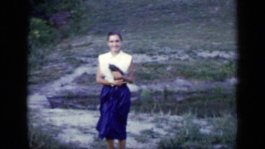 1948: young lady walks toward the camera holding a small kitten, holding it up