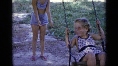 1948: young girl pushes her sister on a swing set, both are laughing NEW YORK