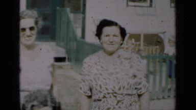 1950: smiling family in front of a home with a green fence NEW YORK