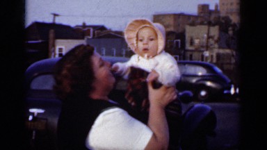 1950: heavy set mother enjoys the company of her little baby as cars pass by