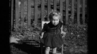 1950: a little girl carefully sits down on a chair in her yard NEW YORK