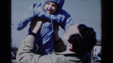 1950: a man holding a child up and making him laugh, while talking to him
