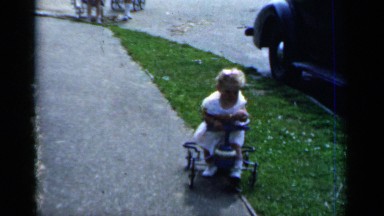 1951: toddler navigates a walker on garden path. NEW YORK