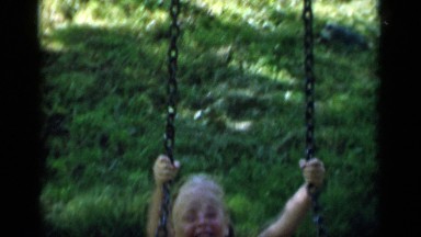 1951: girl wearing two-piece matching outfit moves back and forth on swing