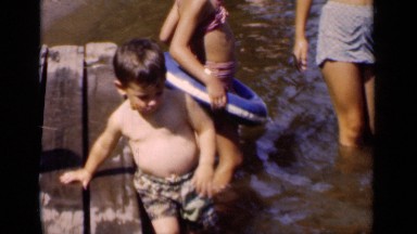1951: a family play in a river while a boy walks toward the camera holding onto