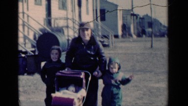 1951: adorable siblings walk toward camera with baby carriage, oldest holds