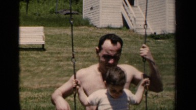 1951: father is his backyard with his son on his lap swinging on a swing set.