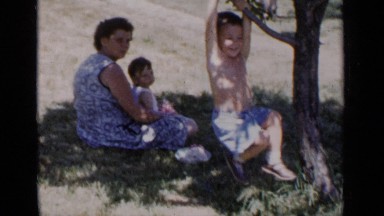 1951: a middle aged woman relaxing in the park while her elder son swings